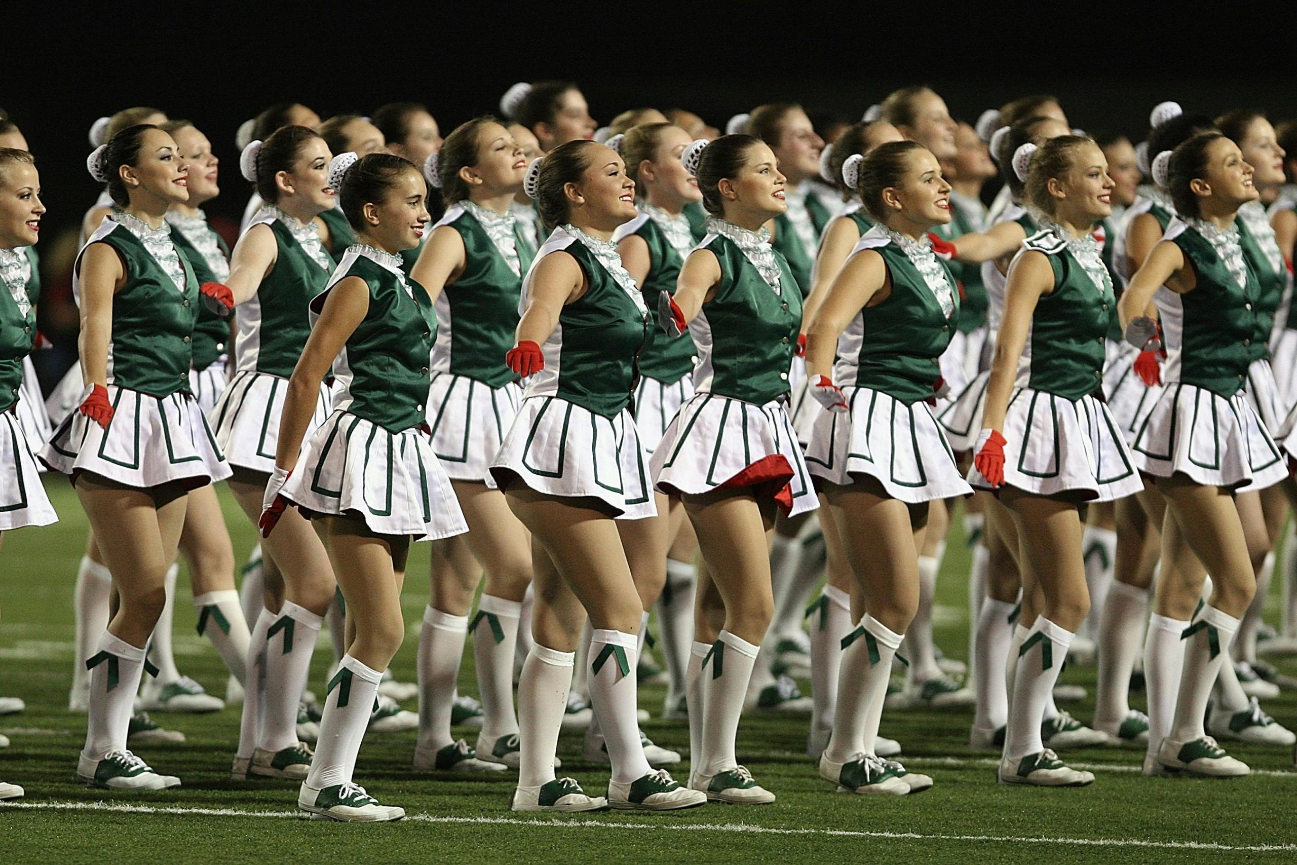 Cheerleading squad performing a synchronized routine at a night football game.
